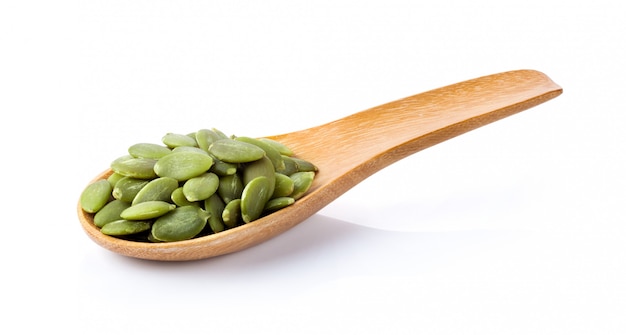 Pumpkin seeds in wood spoon on a white table. 