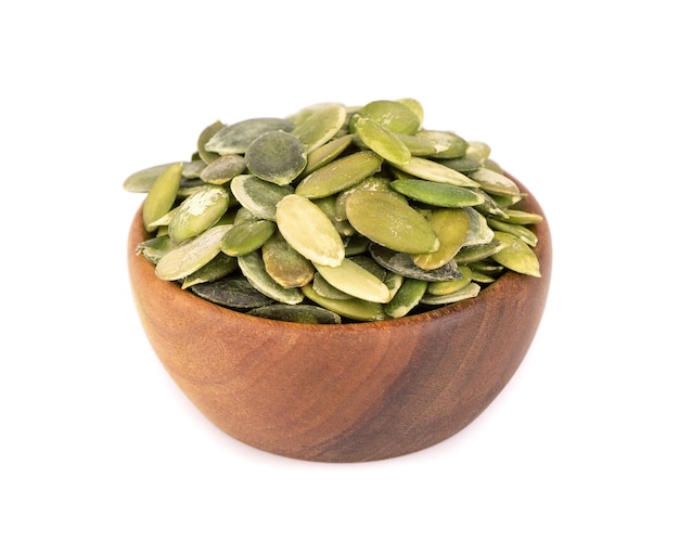 Pumpkin seeds in wooden bowl, isolated on white background. Green pepita seeds.