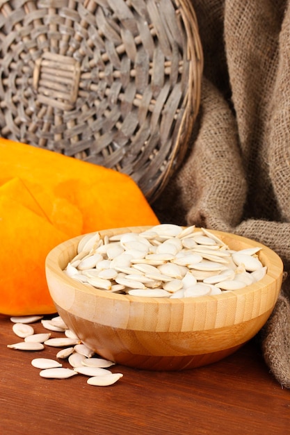 Pumpkin seeds in wooden bowl on sackcloth background