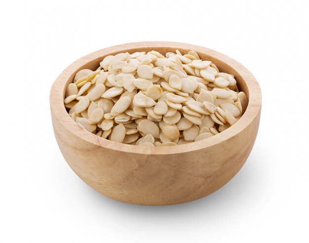 Pumpkin seeds in wooden bowl on white wall