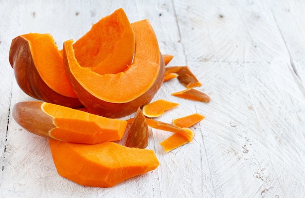 Pumpkin slices on a white wooden background close up