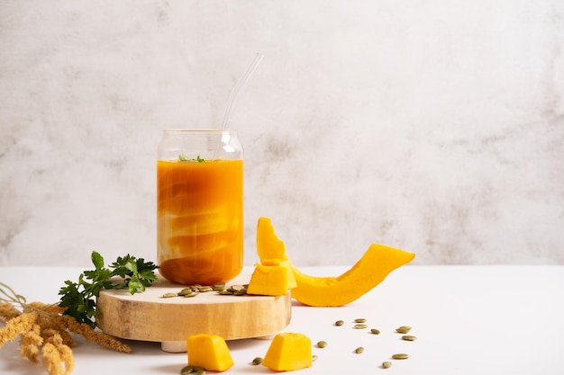 Pumpkin smoothie in a glass jar with a straw Vegan healthy breakfast with pumpkin pieces and seeds