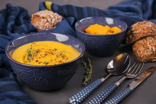 Pumpkin soup in blue bowl topped with fresh herb