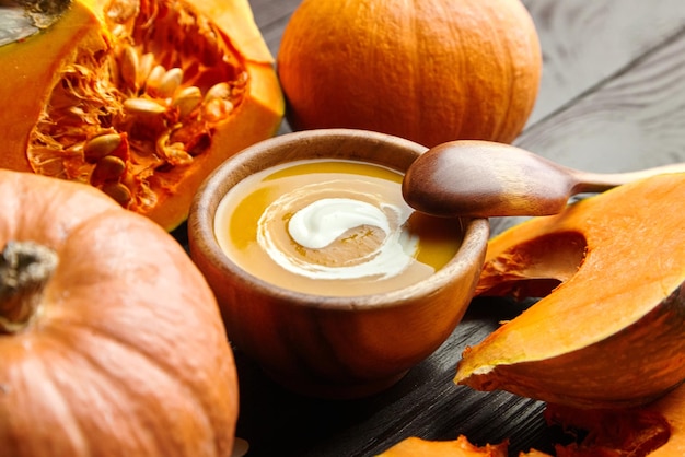 Pumpkin soup in bowl and fresh pumpkins