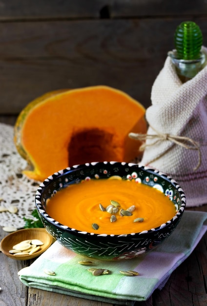 Zuppa di zucca in una ciotola e verdura fresca sul tavolo