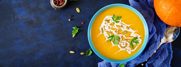 Pumpkin soup in a bowl served with parsley  and pumpkin seeds. Vegan soup.  Thanksgiving day food.