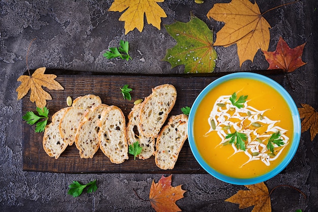 Pumpkin soup in a bowl served with parsley  and pumpkin seeds. Vegan soup.  