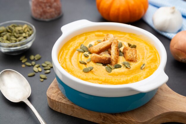 Pumpkin soup in a bowl with fresh pumpkin seeds.
