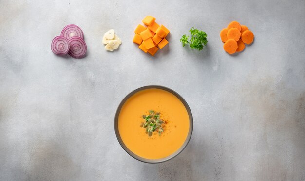 Pumpkin soup in bowl with ingredients