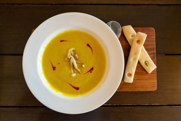 Pumpkin Soup Garnished with Mushrooms  in white plate on wooden table