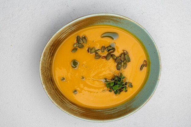Pumpkin soup garnished with pumpkin seeds on a white background