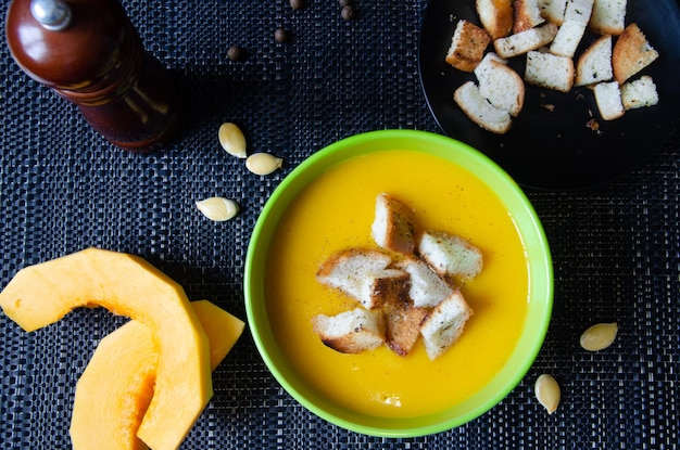 Pumpkin soup in a green cup and pumpkin pieces