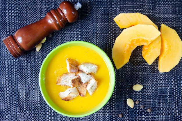 Pumpkin soup in a green cup and pumpkin pieces