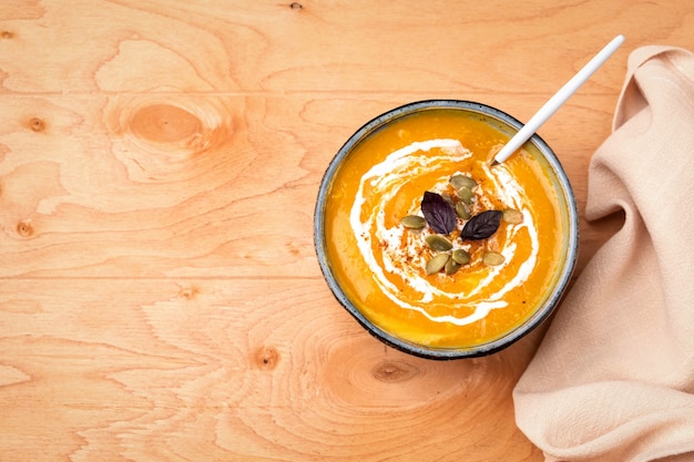 Pumpkin soup in a plate on a wooden surface.