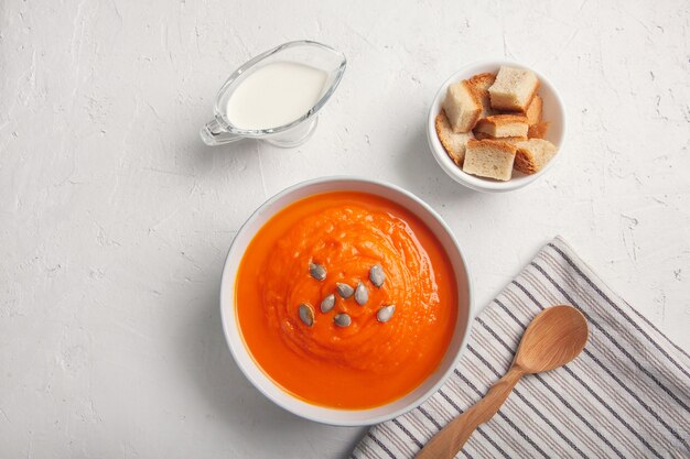 Pumpkin soup-puree with with breadcrumbs, cream and seeds on a white background. Copy space