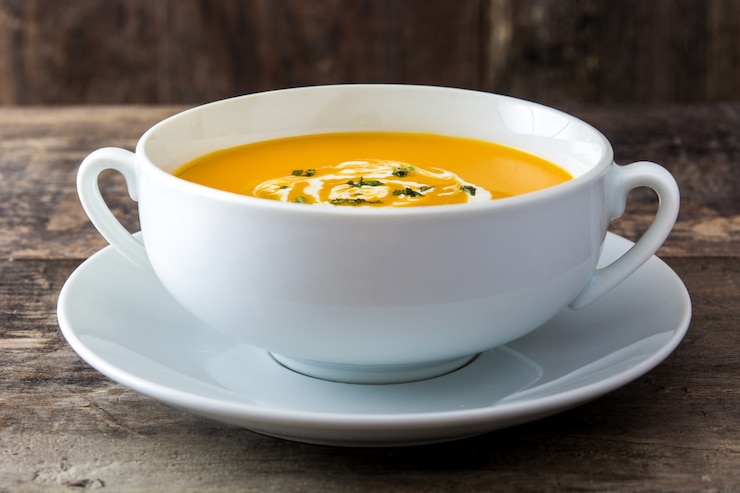 Photo pumpkin soup in white bowl on wooden table