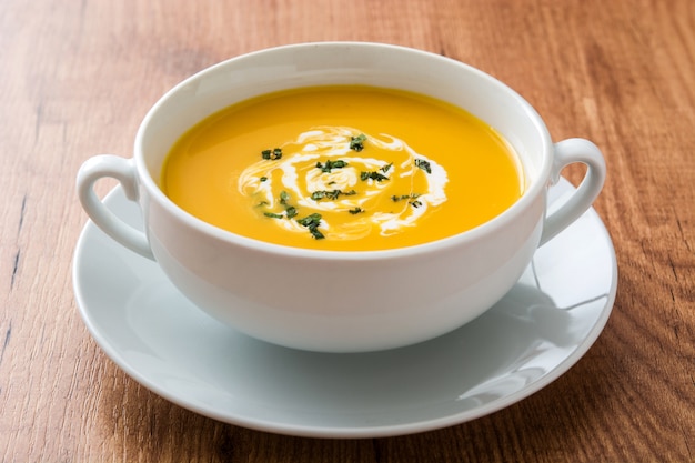 Photo pumpkin soup in white bowl on wooden table