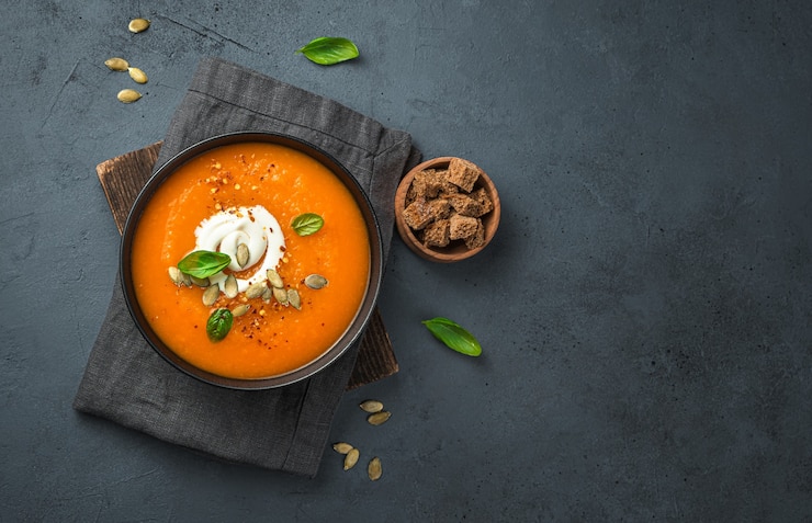 Photo pumpkin soup with cream and carrots on a dark gray background top view copy space