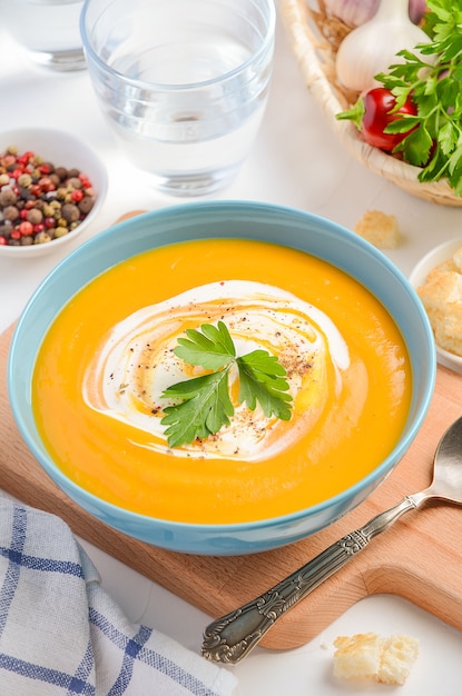 Pumpkin soup with cream and parsley on white background