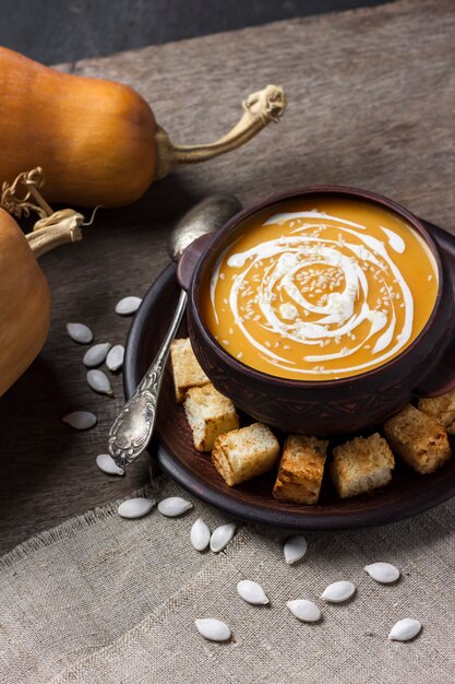 Pumpkin soup with cream and sesame seeds with croutons on wooden background