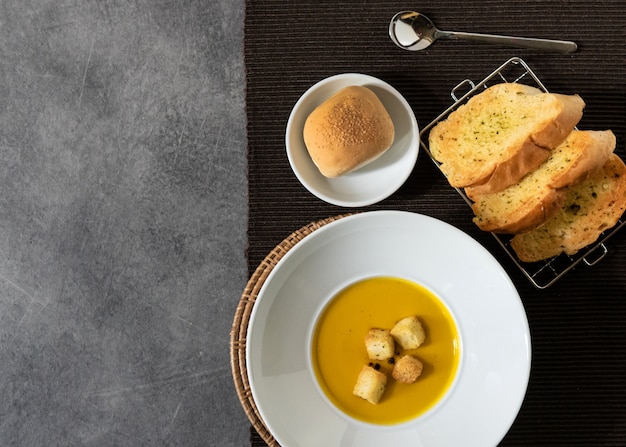 Pumpkin soup with croutons bread in plate garlic bread on stone background with blank copyspace