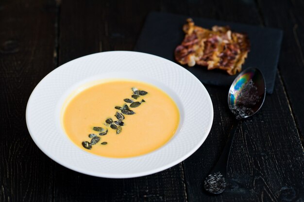 Pumpkin soup with fried bacon in plate