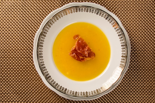 Pumpkin Soup with prosciutto on table