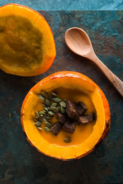 Pumpkin soup with seeds and croutons in a pumpkin and a spoon