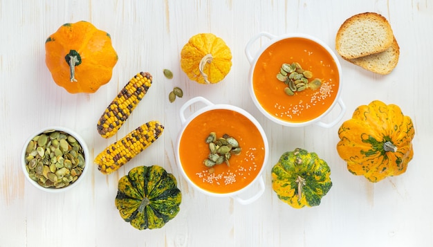 Pumpkin soup with seeds on white wooden background Top view