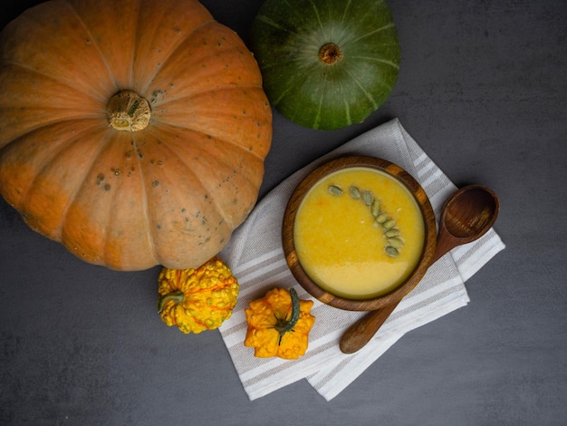 Pumpkin soup in wooden bowl on grey background