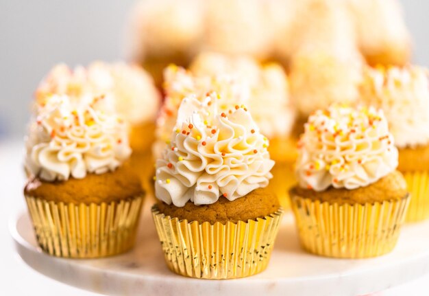 Pumpkin spice cupcake met Italiaanse botercrème en hagelslag op een taartplateau.