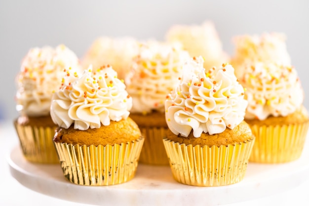 Pumpkin spice cupcake with Italian buttercream and sprinkles on a cake stand.