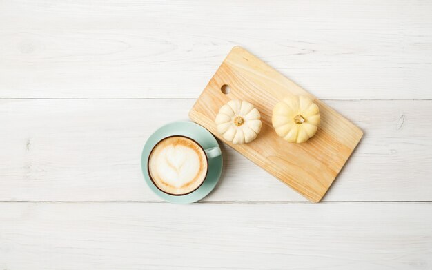 パンプキンスパイスラテ。泡と小さな黄色のカボチャと青いコーヒーカップ。秋の秋のホットドリンク、カフェ、バーのコンセプト、トップビュー