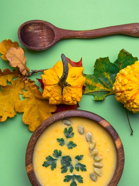 Pumpkin squash vegetable soup with pumpkin seeds parsley in a wooden bowl on green background Pumpkin Squash soup Creamy soup Vegetable soup