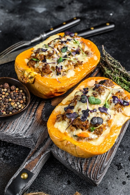 Zucca ripiena di carne di manzo tritata, verdure ed erbe sfondo nero. vista dall'alto.