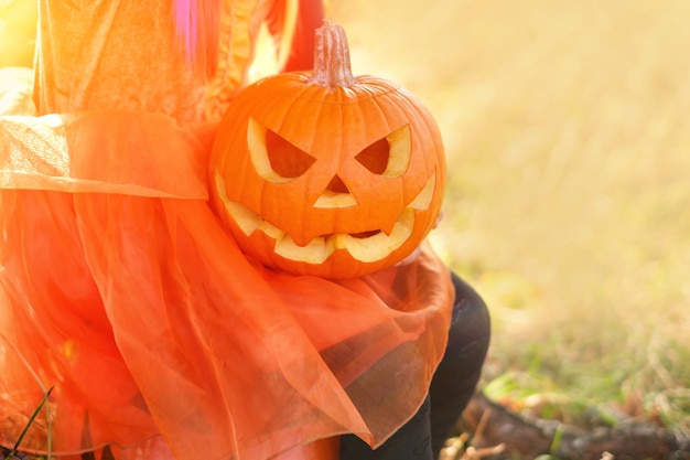 Pumpkin with an evil face in the hands of a child on Halloween