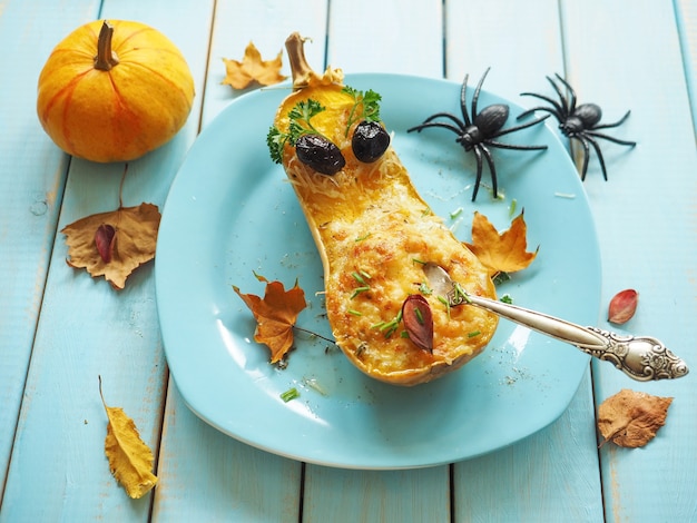 Photo pumpkin with yellow leaves on blue background funny halloween background