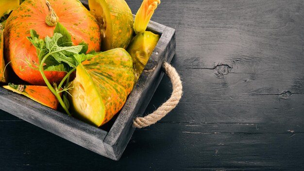 Pumpkin in a wooden box pumpkin sliced on a wooden table free space for text top view