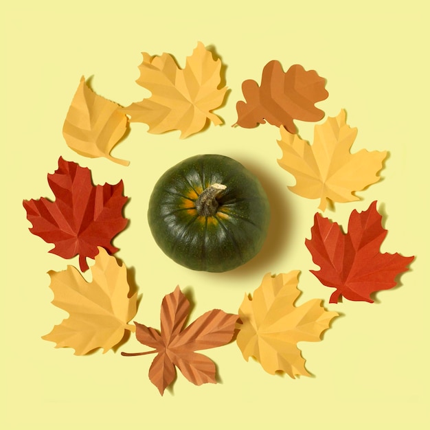 Pumpkin in wreath of paper autumn leaves