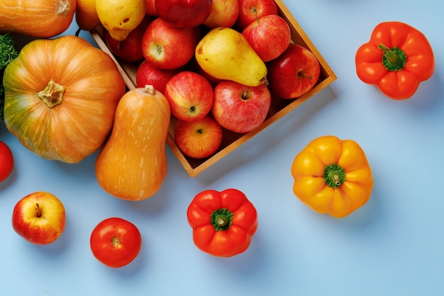 Pumpkins, apples and bell pepper composition on blue background top view