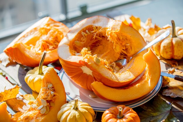 Pumpkins and cut pieces on plate on wooden table