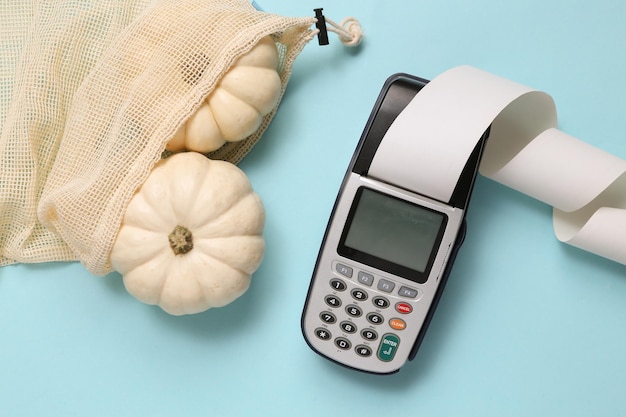 Pumpkins in eco bag payment terminal on blue background