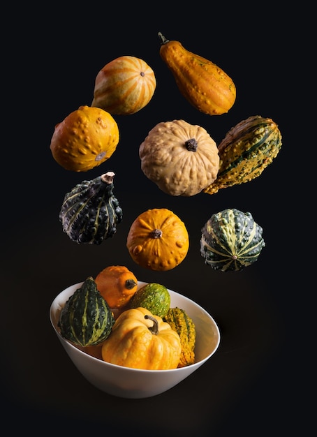 Pumpkins falling into a bowl with dark background