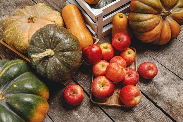 Pumpkins and red apples on wooden surface