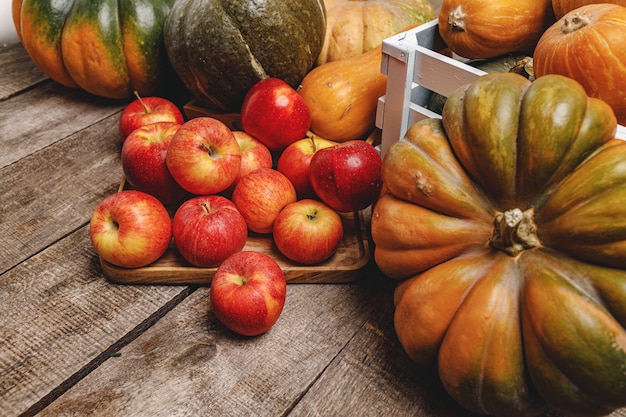 Pumpkins and red apples on wooden surface