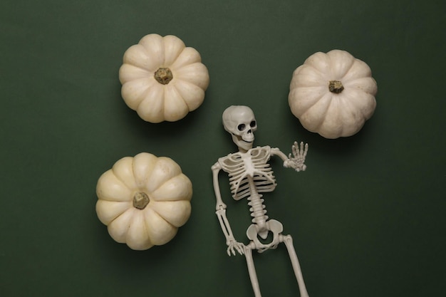 Pumpkins and skeleton on a green background Halloween decor Flat lay Top view