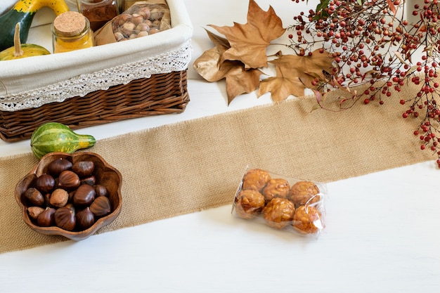 Zucche spezie e nocciole confezionate in cesto regalo artigianale castagne e panelles de piones sul bianco tavolo rustico