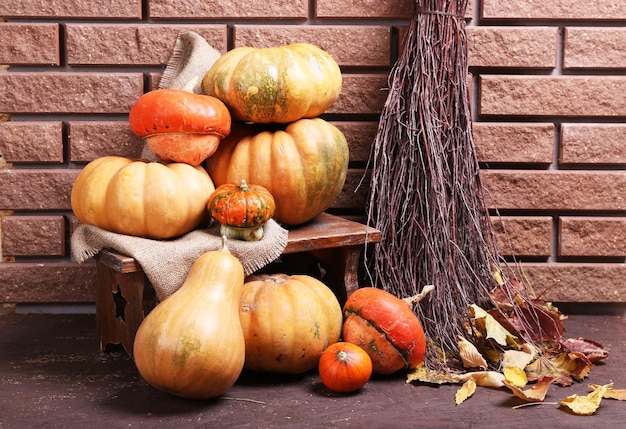 Pumpkins on stool on floor on brick wall background