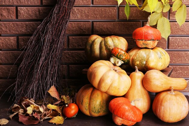 Pumpkins on stool on floor on brick wall background