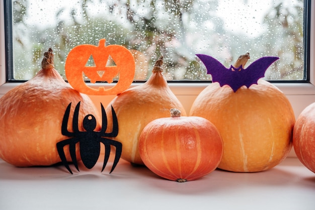 Pumpkins with handmade felt halloween ornaments on the windowsill background